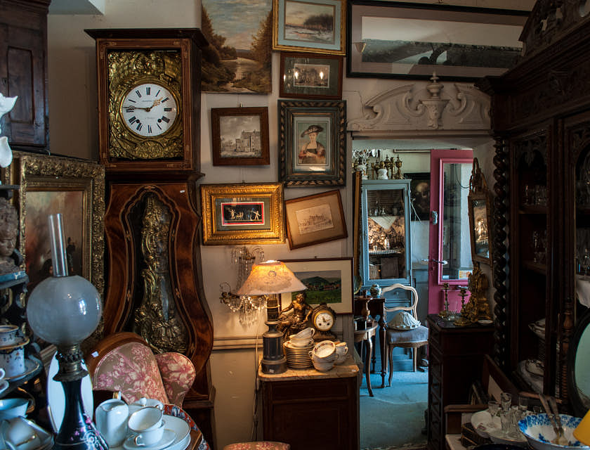 Un magasin d'antiquités avec meubles, tableaux et verrerie.