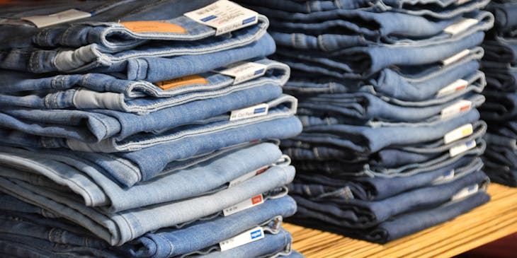 Apparel stacked on wooden shelf.