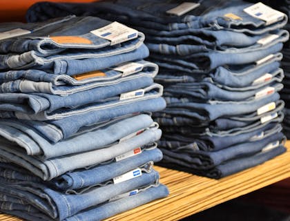 Apparel stacked on wooden shelf.