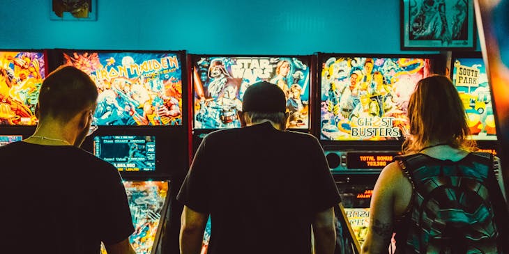 Three gamers playing on an arcade machine.
