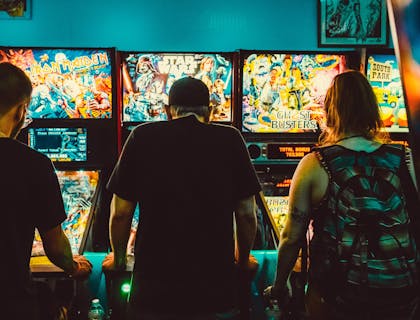 Três pessoas jogando em um salão de jogos.