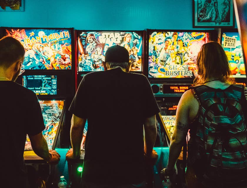 Three gamers playing on an arcade machine.