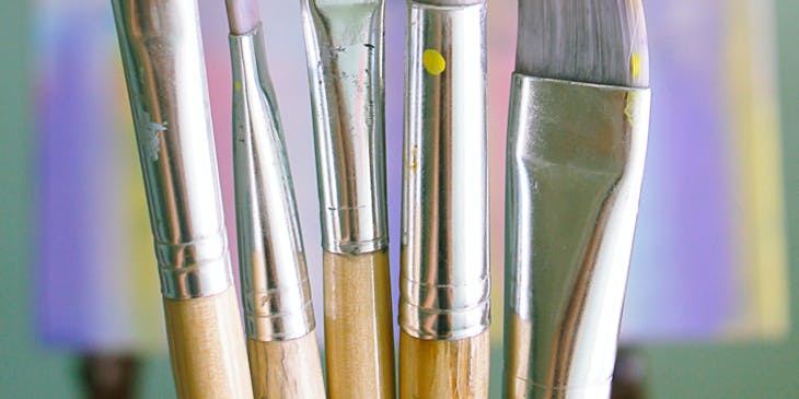 Paint brushes with paint on them in an art class.