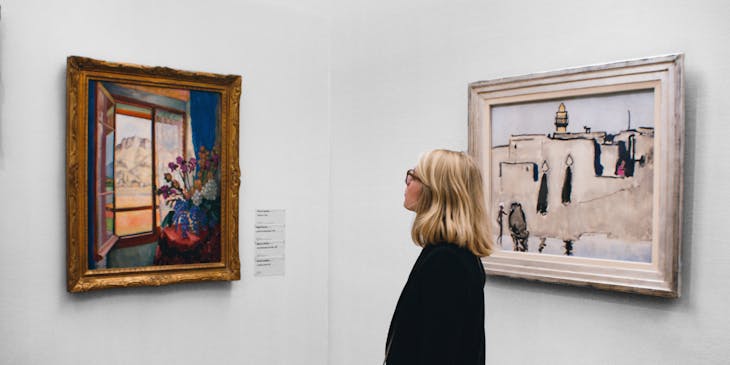 A woman admires a painting at an art gallery.