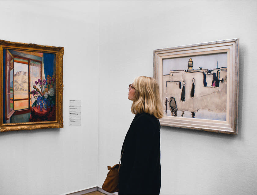 Una mujer admira una pintura en una galería de arte.