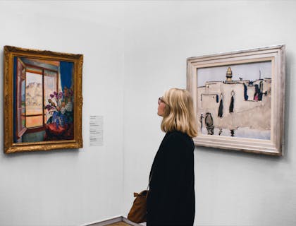 A woman admires a painting at an art gallery.