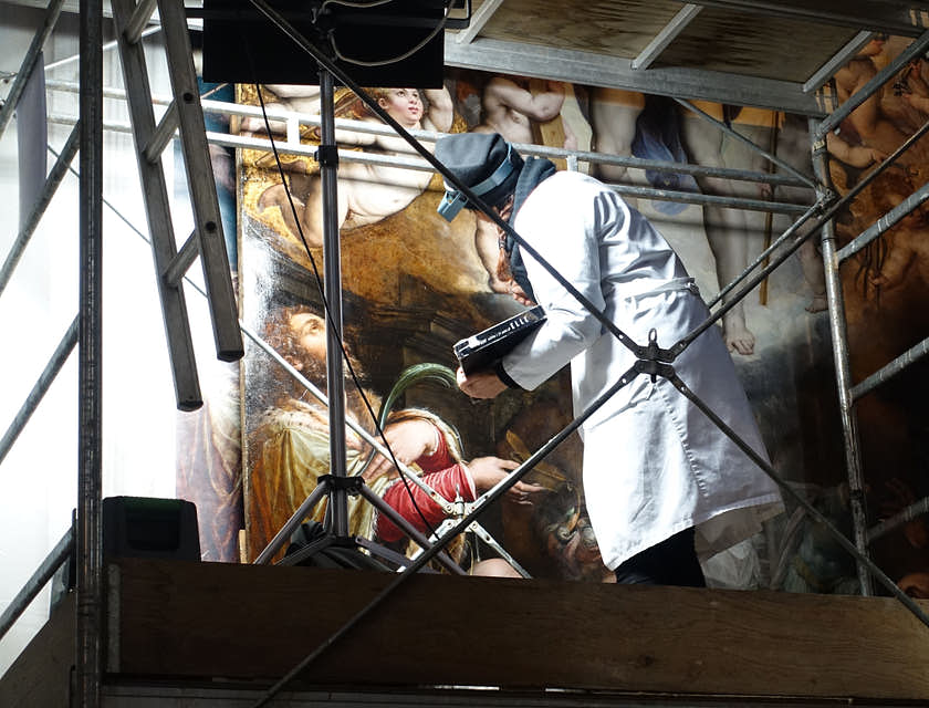Une femme entrain de restaurer une œuvre d'art de la renaissance.