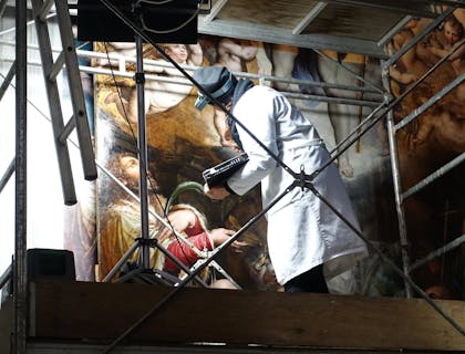 A woman working in art restoration on renaissance piece.