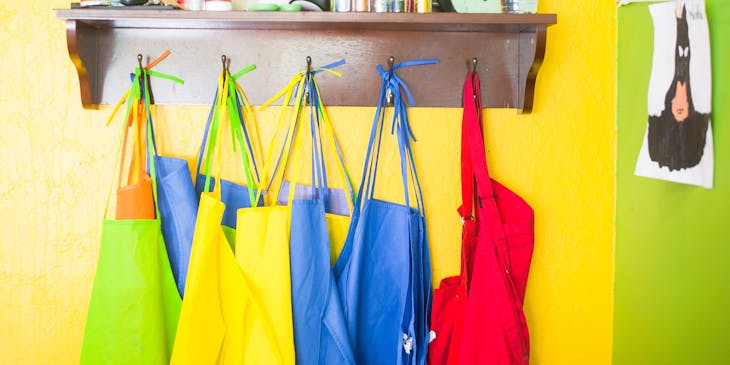 Des tabliers colorés accrochés à un porte-manteaux dans une école d'art.