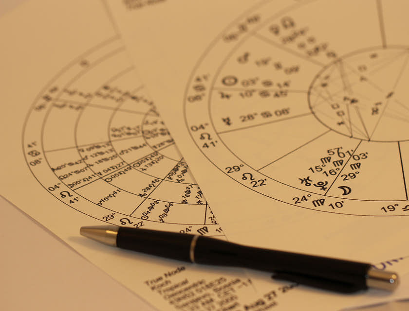 Un stylo posé sur des cartes d'astrologie.