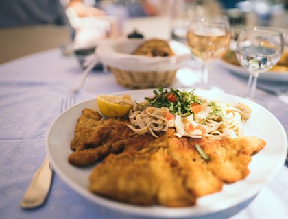Comida servida en un plato con copas al fondo en un restaurante austriaco.