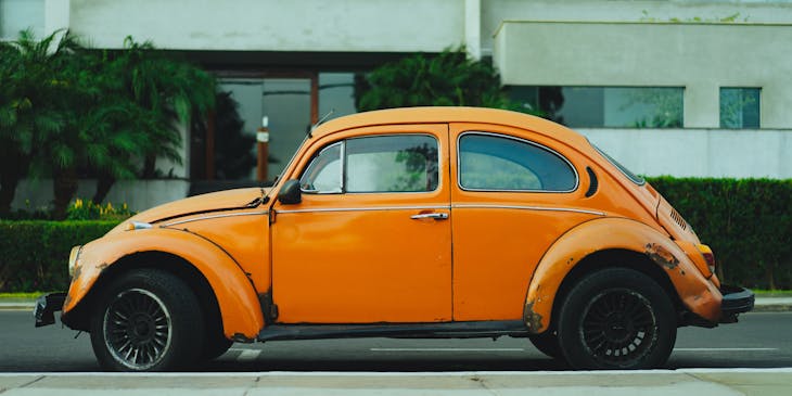 Orange Volkswagen beetle on a street outside an auto insurance business.