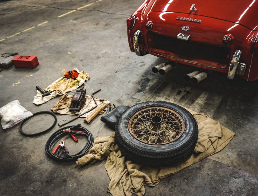 carro vermelho perto de um pneu e alguns equipamentos em uma oficina de reparos.