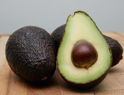 Tre avocado su un tavolo di legno.