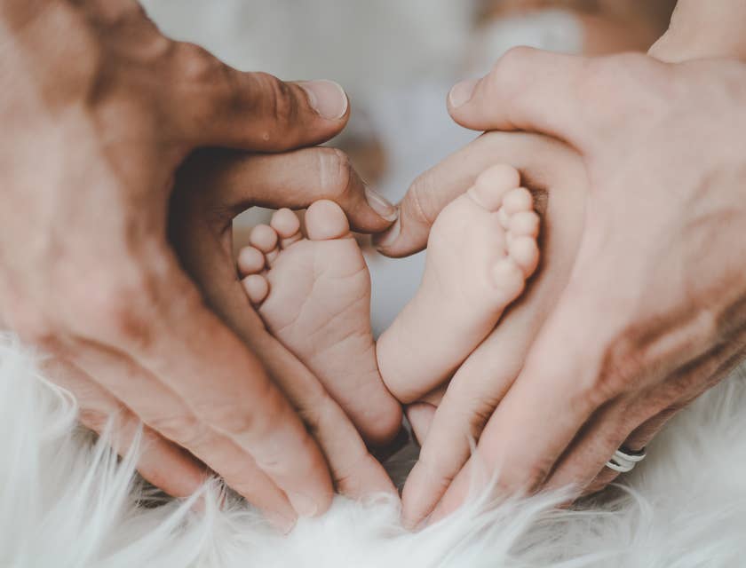 Mãe e pai segurando os pés do bebê formando um coração.