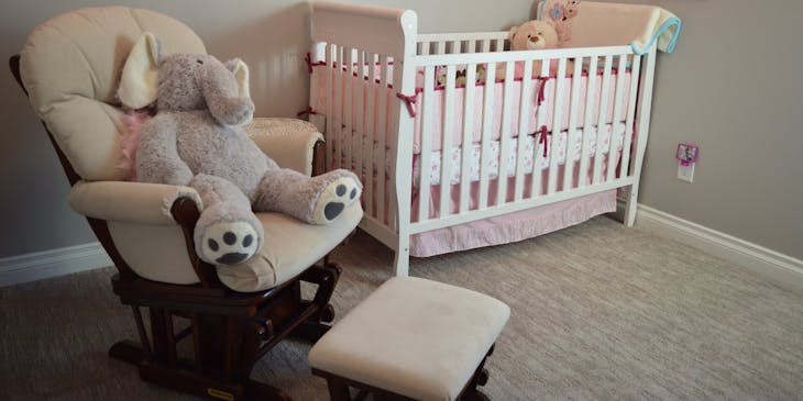 Comfy rocking chair and foot stool positioned next to a crib on display at a baby gear and furniture business.