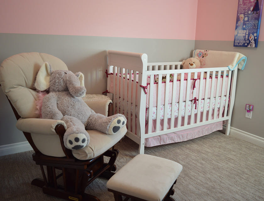 Une chaise à bascule confortable et un pouf placés à côté d'un berceau exposé dans un magasin d'articles et de meubles pour bébés.