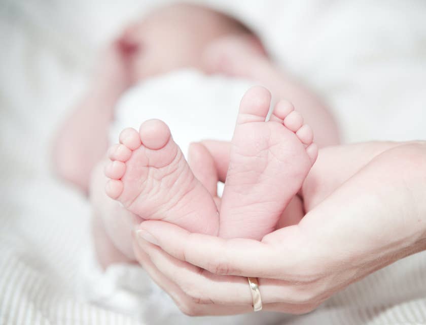 Eine Mutter hält während eines Babyfotoshootings sanft die Füße ihres Neugeborenen in den Händen.