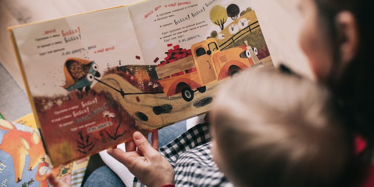 Babysitter reading a book to a child.