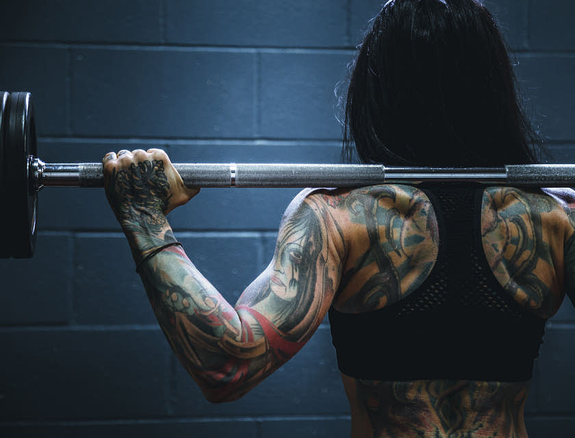 Una donna tosta e tatuata che fa i pesi.