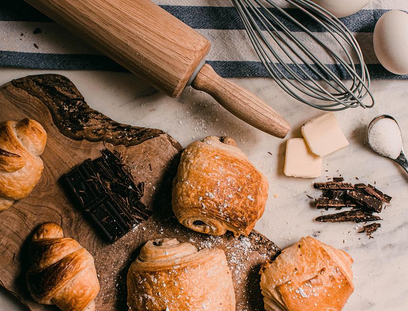 Matériel de pâtisserie, ingrédients et produits sur une planche à découper en bois et un torchon bleu et blanc.