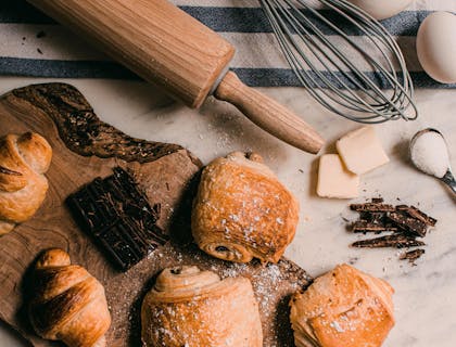 Matériel de pâtisserie, ingrédients et produits sur une planche à découper en bois et un torchon bleu et blanc.