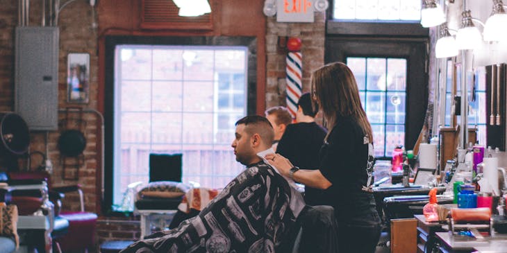 Barber working on a male client's hair in a barbershop.