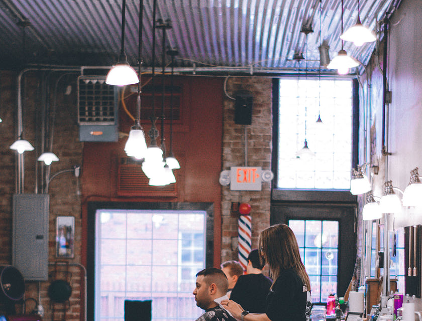Barbero trabajando en el cabello de un cliente masculino en un negocio de barbería