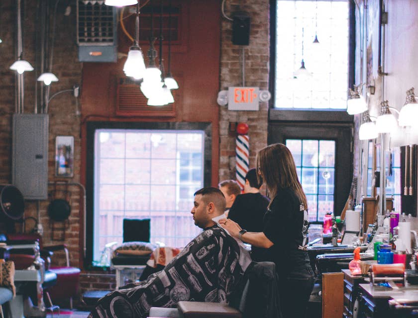 Ein Barbier stutzt die Bart- und Nackenhaare eines männlichen Kunden.
