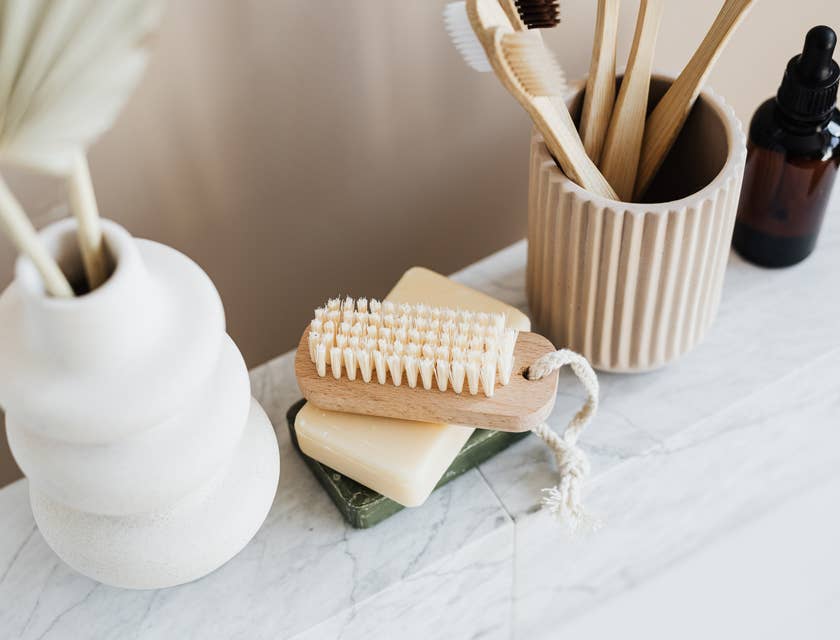 Conjunto de produtos de banho como sabonetes, escovas e óleo essencial em cima de uma mesa de mármore.