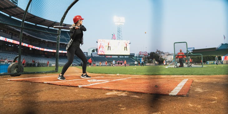Una giocatrice di baseball che si allena in una batting cage.