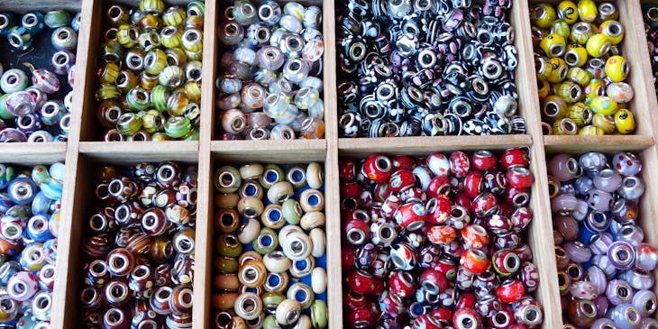 Assorted glass beads in a wooden display tray in a bead store.