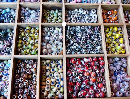 Assorted glass beads in a wooden display tray in a bead store.