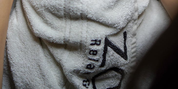 A woman with a white towel on her head having a facial at a beauty bar.