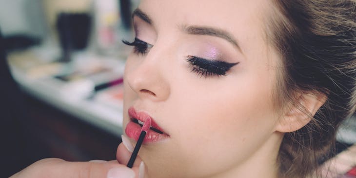 A beautician applying red lipstick to a client in a beauty parlour business.