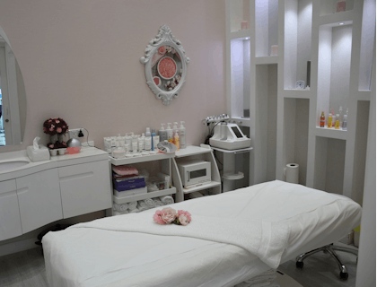 A room in a beauty salon that includes a massage bed, vanity, and beauty supplies.