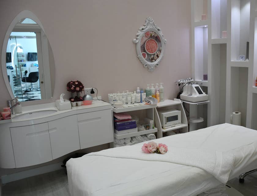 A room in a beauty salon that includes a massage bed, vanity, and beauty supplies.