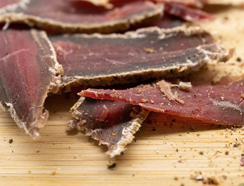 Fette di carne secca su un tagliere di legno prodotte in un’azienda di carne secca.