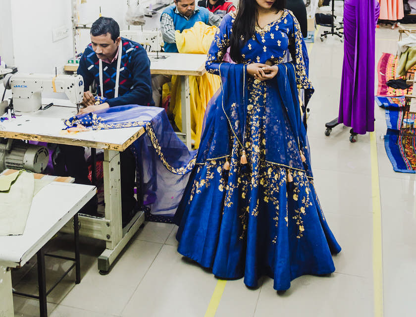 Mujer con un vestido azul acompañada de un sastre en un negocio de sastrería a medida