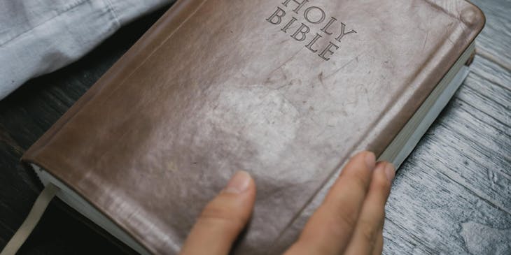 A man's hands holding a Bible and a cross.