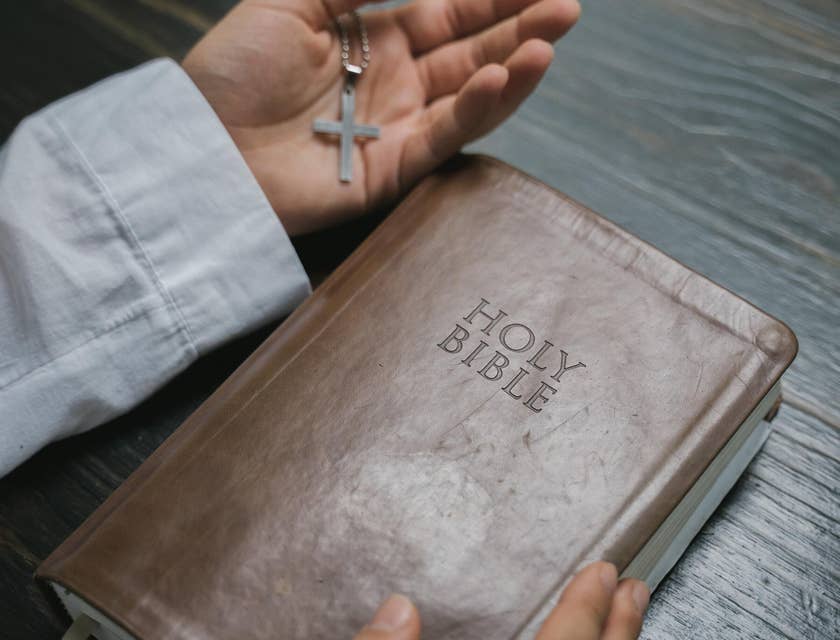 Les mains d'un homme tenant une Bible et une croix.