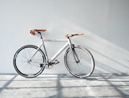 Una bicicleta blanca recargada sobre una pared blanca.