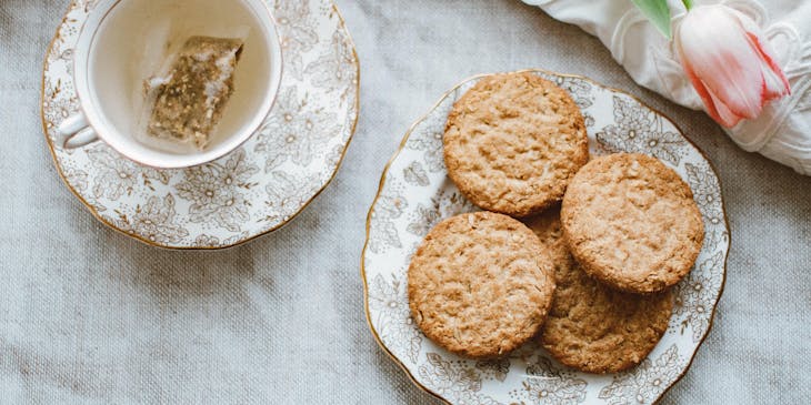 Biscuits on a plate next to a tea cup.