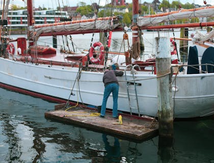 A man from a boat cleaning business washing a boat.