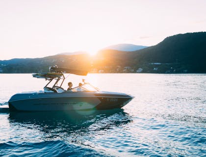 Barco adquirido en un negocio de distribuidores de barcos en el agua durante la puesta de sol.