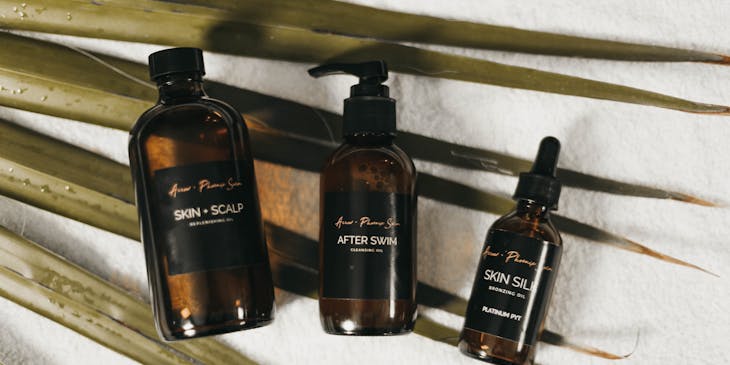 Body products on a white surface with leaves beneath them