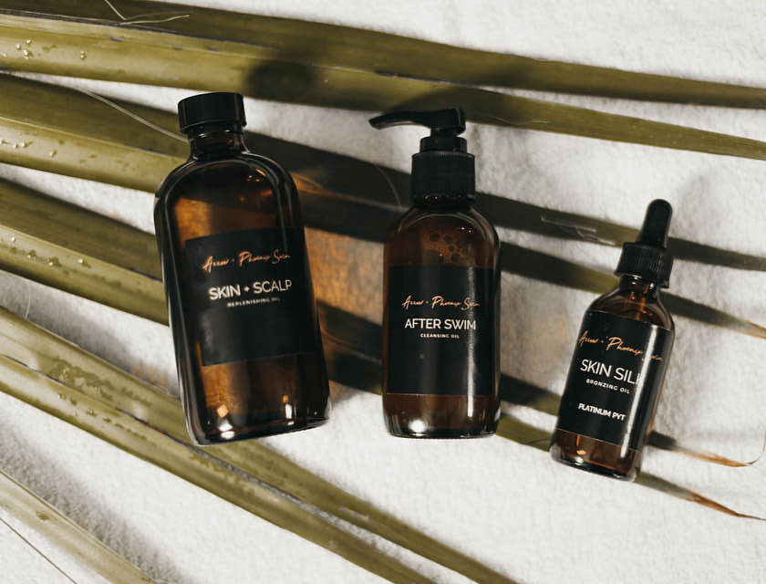 Des produits de soins corporels sur une surface blanche avec des feuilles en dessous