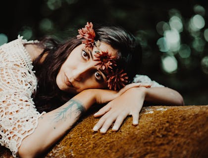 Una mujer vestida en un estilo bohemio con tatuajes bohemios acostada sobre un sofá en un negocio con nombre bohemio.