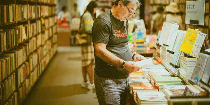 A man reading a book inside a bookstore.
