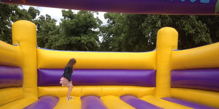 A child jumping on a purple and yellow bounce house.